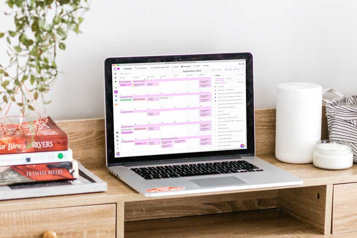 Apple MacBook Pro on desk showing ClickUp calendar view