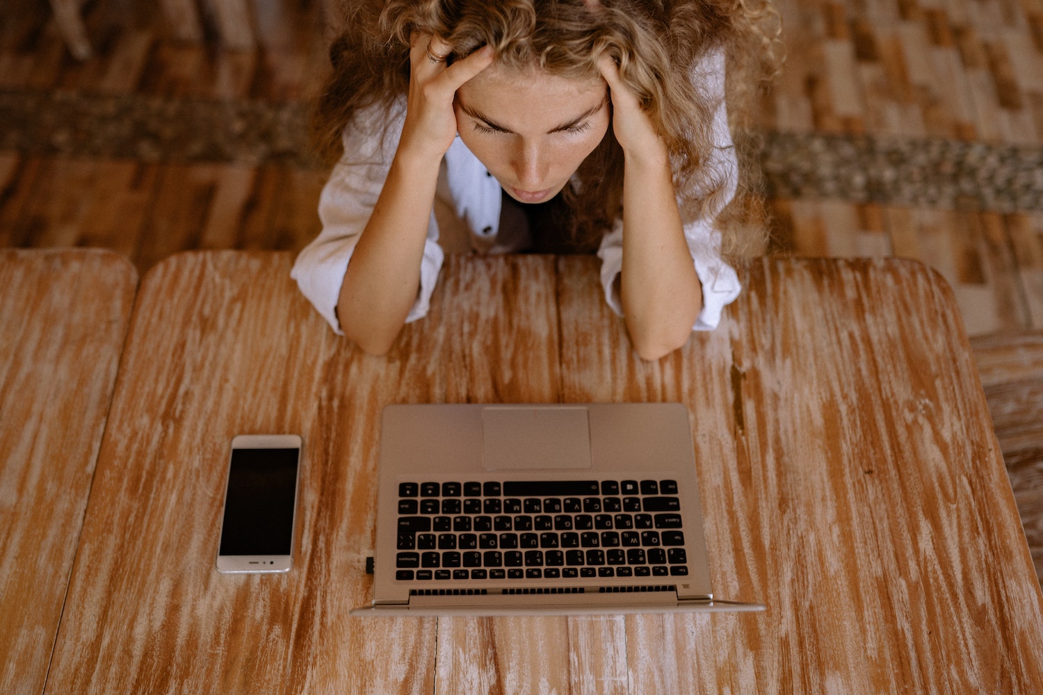 person holding their head in frustration in front of laptop